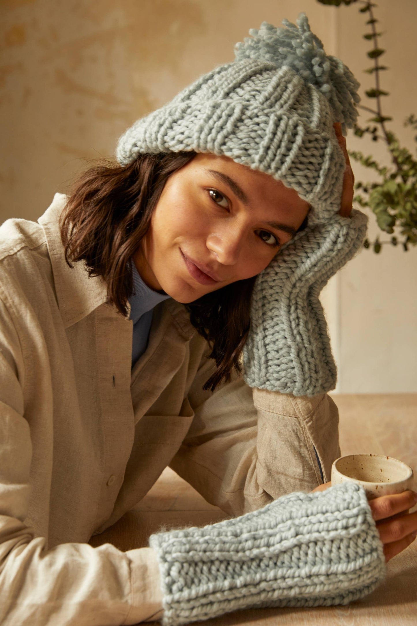Woman wearing knit hat with pom pom and fingerless gloves