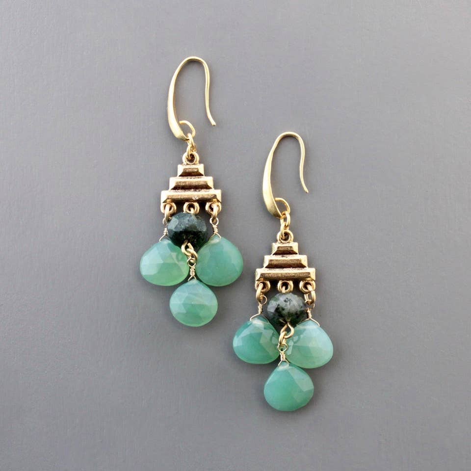 Close up of gold tone earring with hook,, stack of three pyramid gold bars, and 4 stones dangling below, 3 light teradrops in aqua and one round dark grey. Against a light grey background.