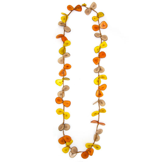 Close up of necklace made of cord and dyed slices of tagua nut against a white background. Necklace is orange, saffron yellow, and taupe.