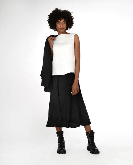 Model wearing a sleveless cream top, black full skirt, and black combat boots. On a white background.