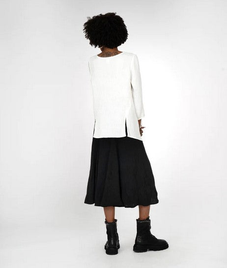 Back view of Model wearing a cream top, black full skirt, and black combat boots. On a white background.