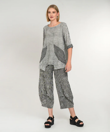 blond model wearing white stripe top with black pockets and black stripe pants and black sandals. on a white background.