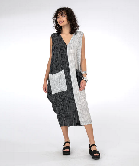 model wearing v-neck dress that is half white print and half black print with a center seam and large contrast print pocket on the front. on a white background