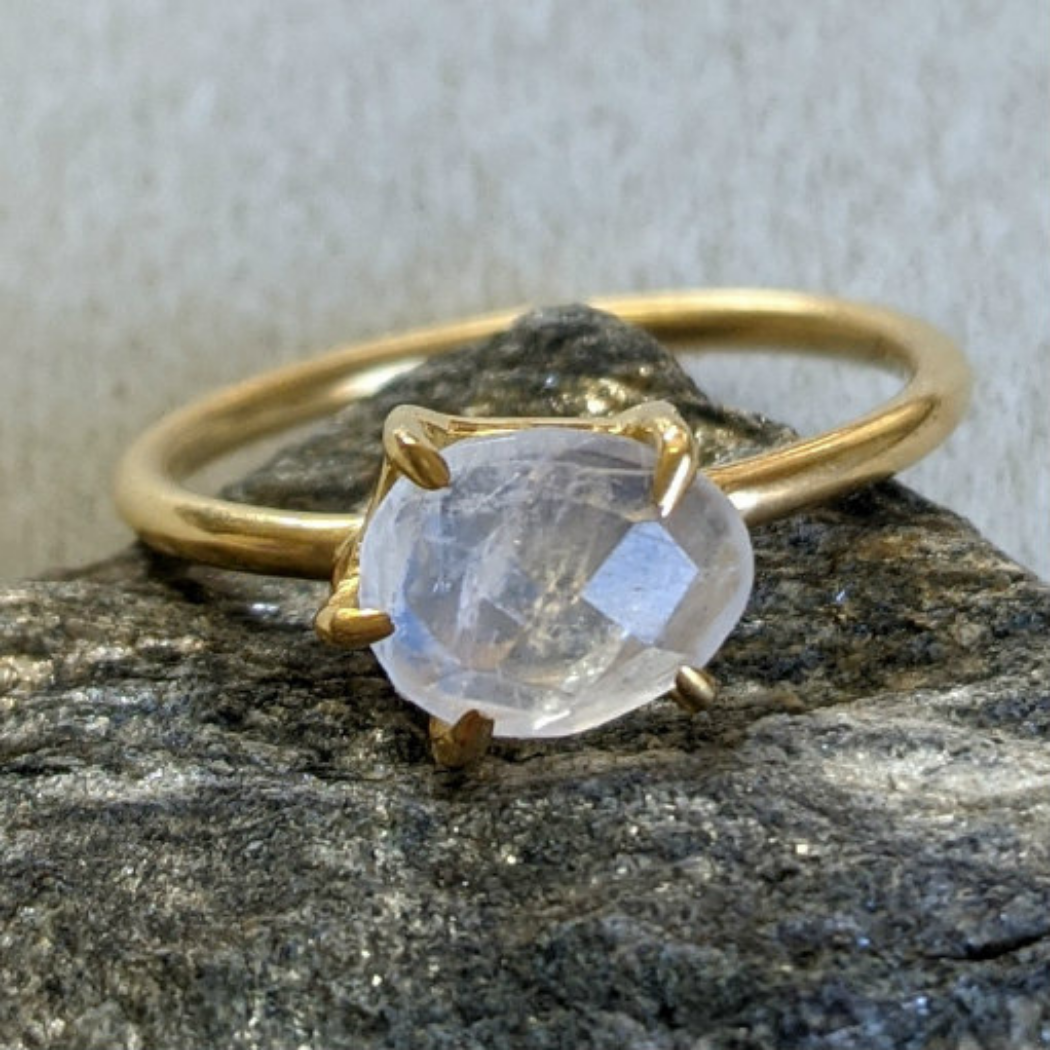 Faceted oval rainbow moonstone in a 5-pronged bezel 18k vermeil ring on a rock