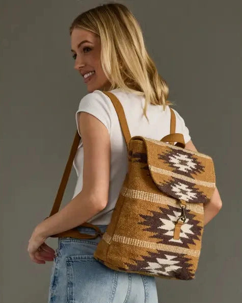 Woman carrying a brown and beige patterned backpack against a gray background