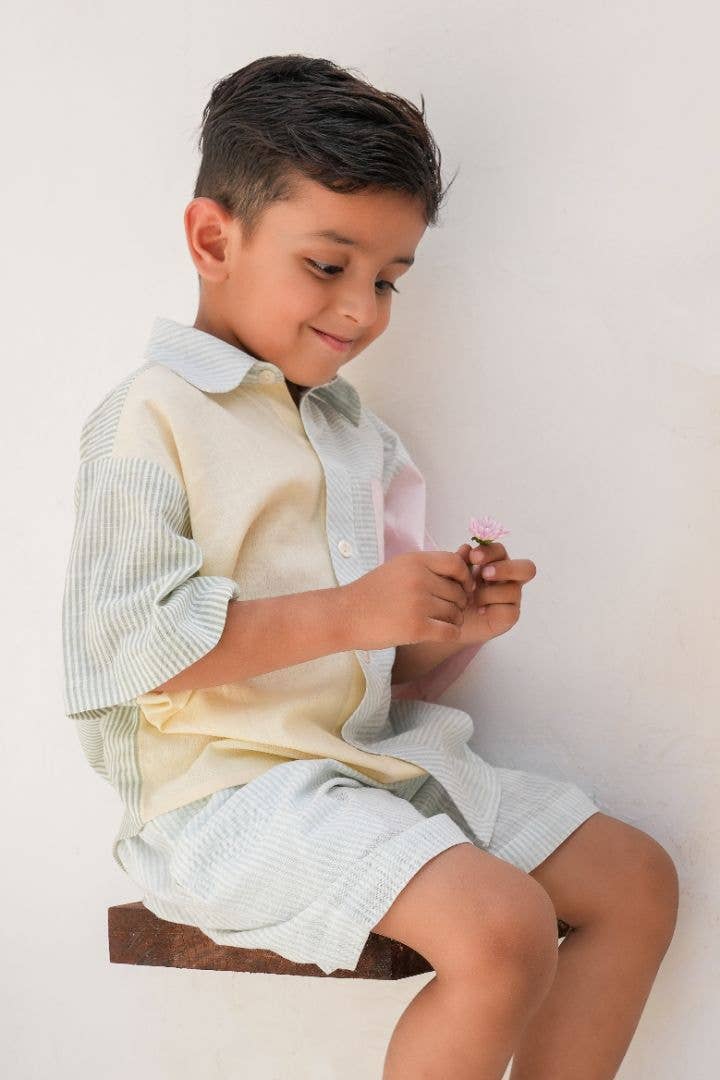 Young boy sitting and holding a small object against a plain background