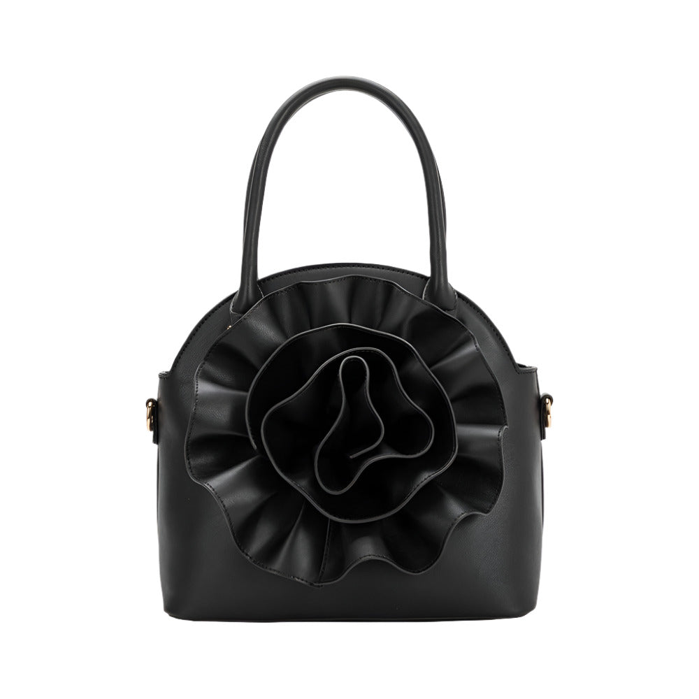 black handbag with large flower detailing on white background