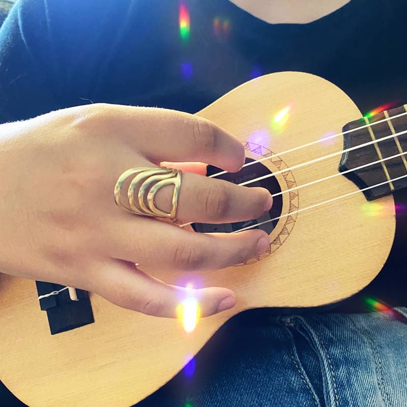 close-up of model holding a ukelele with an abstract gold ring