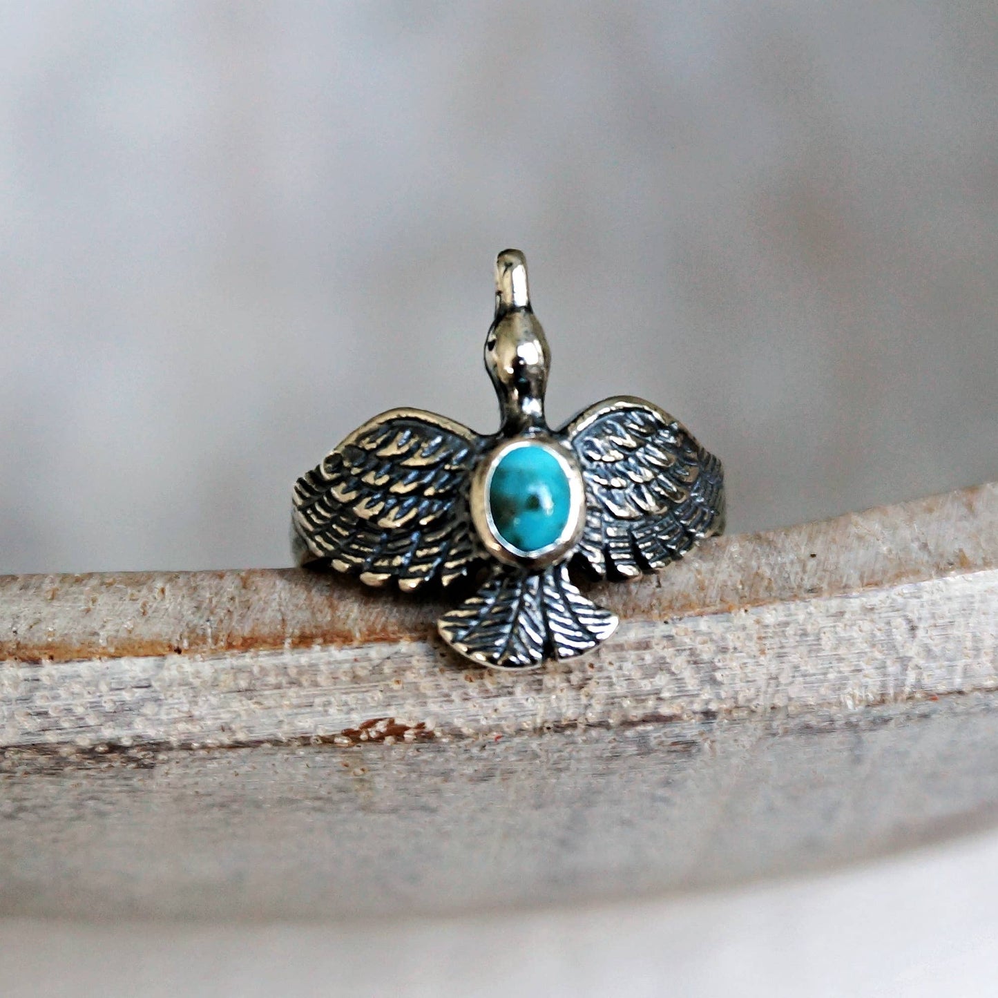 Silver pendant with turquoise stone on a wooden surface