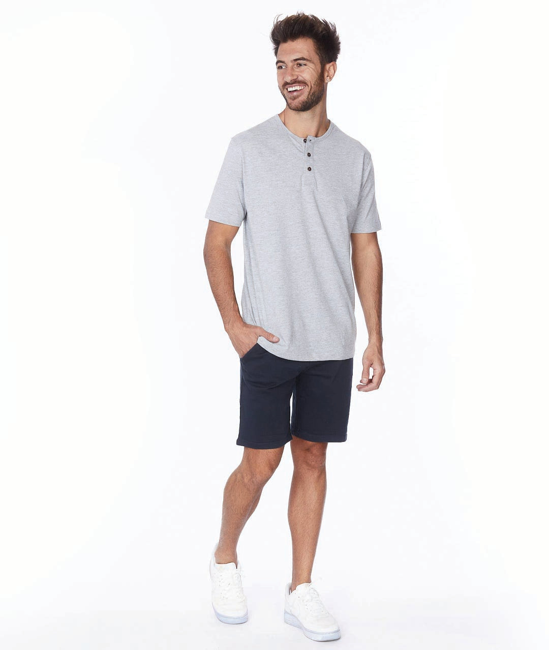Male model wearing navy shorts with a grey tee and white sneakers.