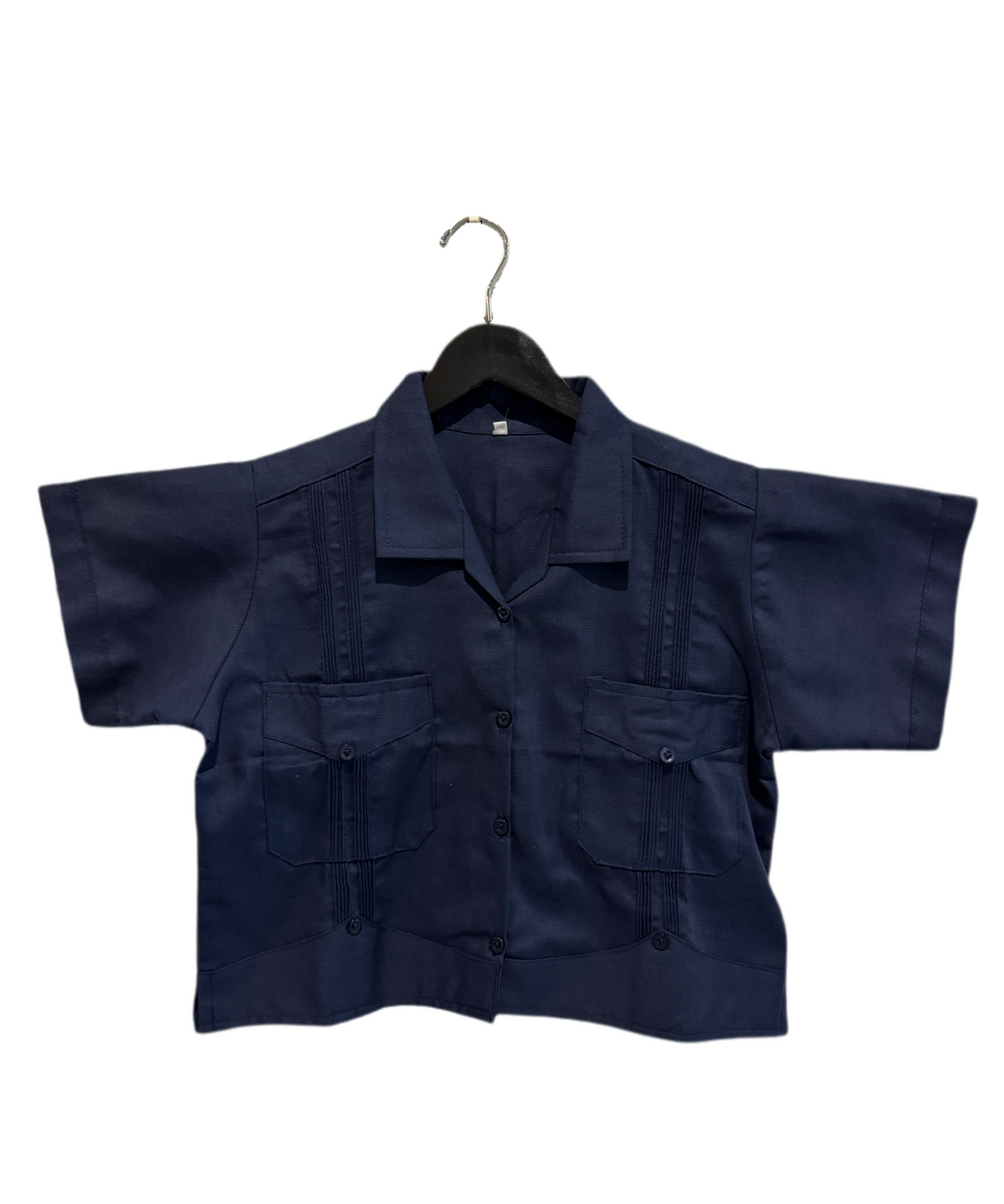 A dark navy blue short-sleeve button-up shirt with vertical pleats on the chest and two front flap pockets, hanging on a black hanger against a plain white background.