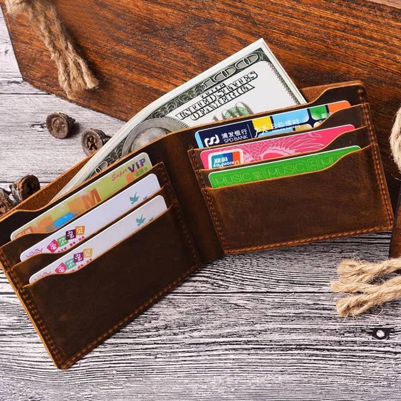 brown leather wallet opened with cards and cash inside, on top of wood surface 