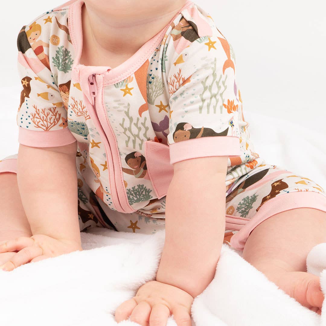 Baby wearing a colorful outfit with sea-themed design on a white background