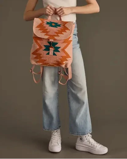 Woman holding a patterned backpack against a plain background