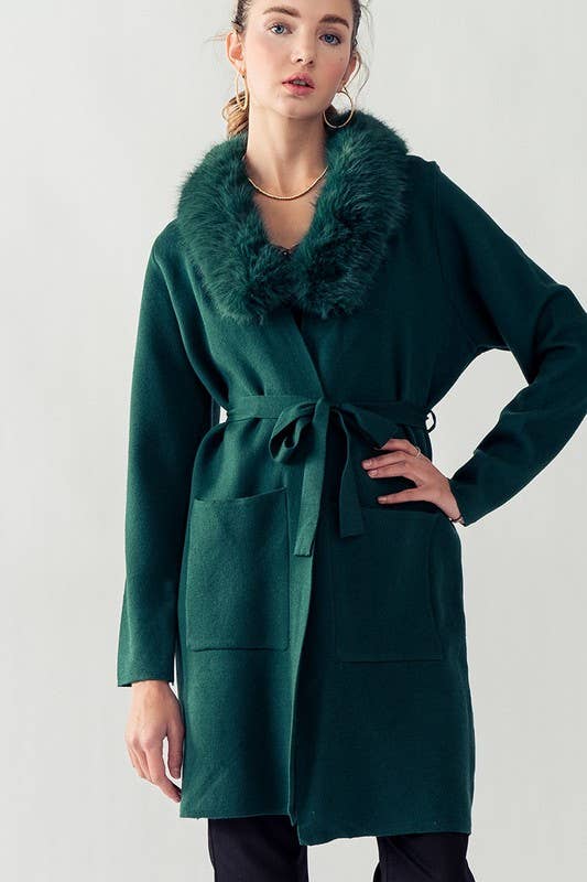 model wearing hunter green cover up featuring two front pockets, tie belt and fur collar