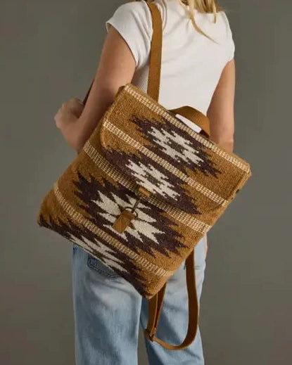Woman carrying a brown patterned tote bag against a plain background