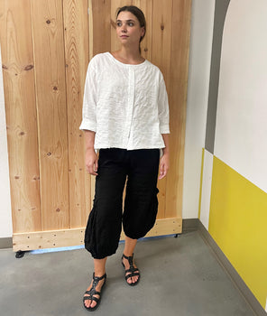 model in a black cargo pant with dropped pockets, worn with a white top with a false placket and rolled sleeves