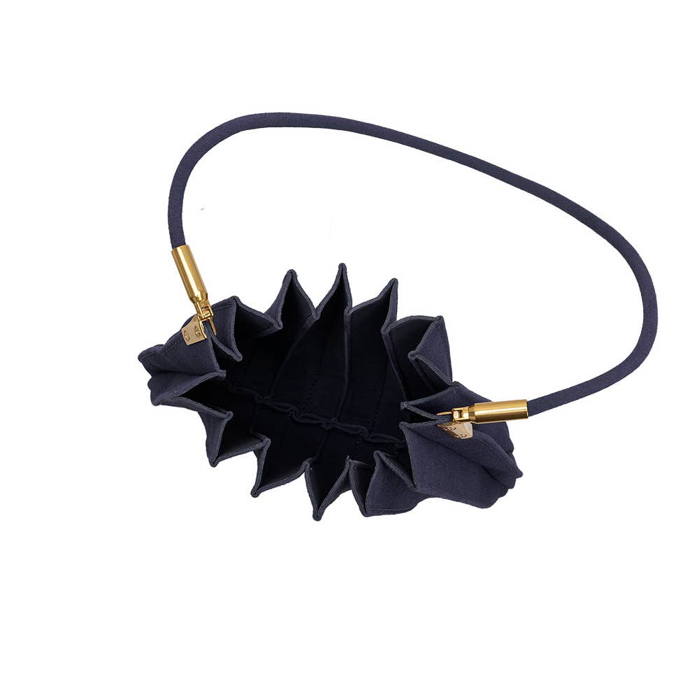 A black pleated fabric wristlet bag with a matching black elastic strap and gold-tone metal hardware, shown on a plain white background.