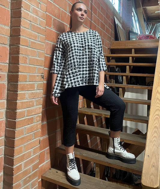 model in a black textured crop length pant with a matching shirt in a black and white plaid
