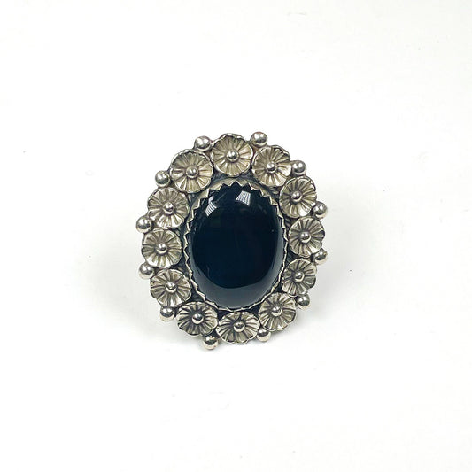 Oval Black onyx stone ring with silver metal flowers surrounding the stone.