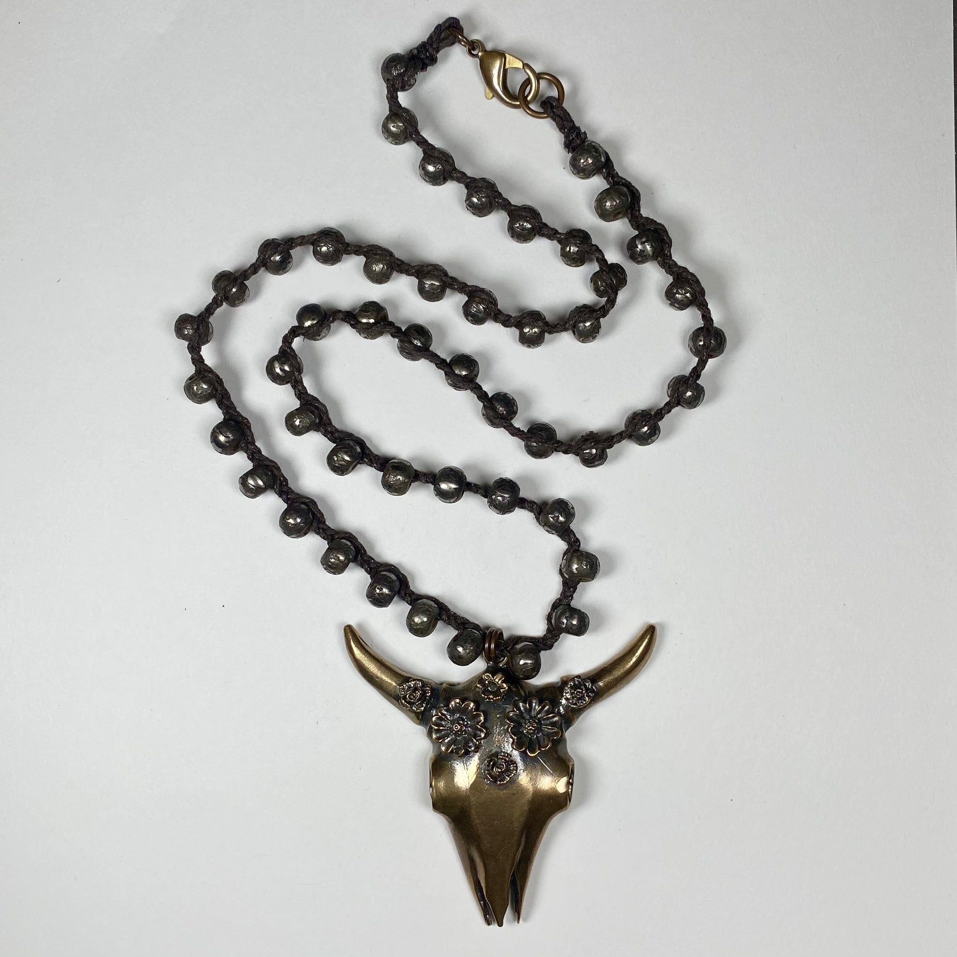 Bronze Cattle skull with flower crown pendant on a necklace of dark dyed bronze beads.