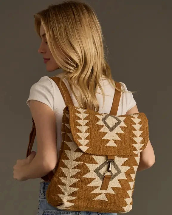 Woman wearing a brown and beige patterned backpack against a plain background