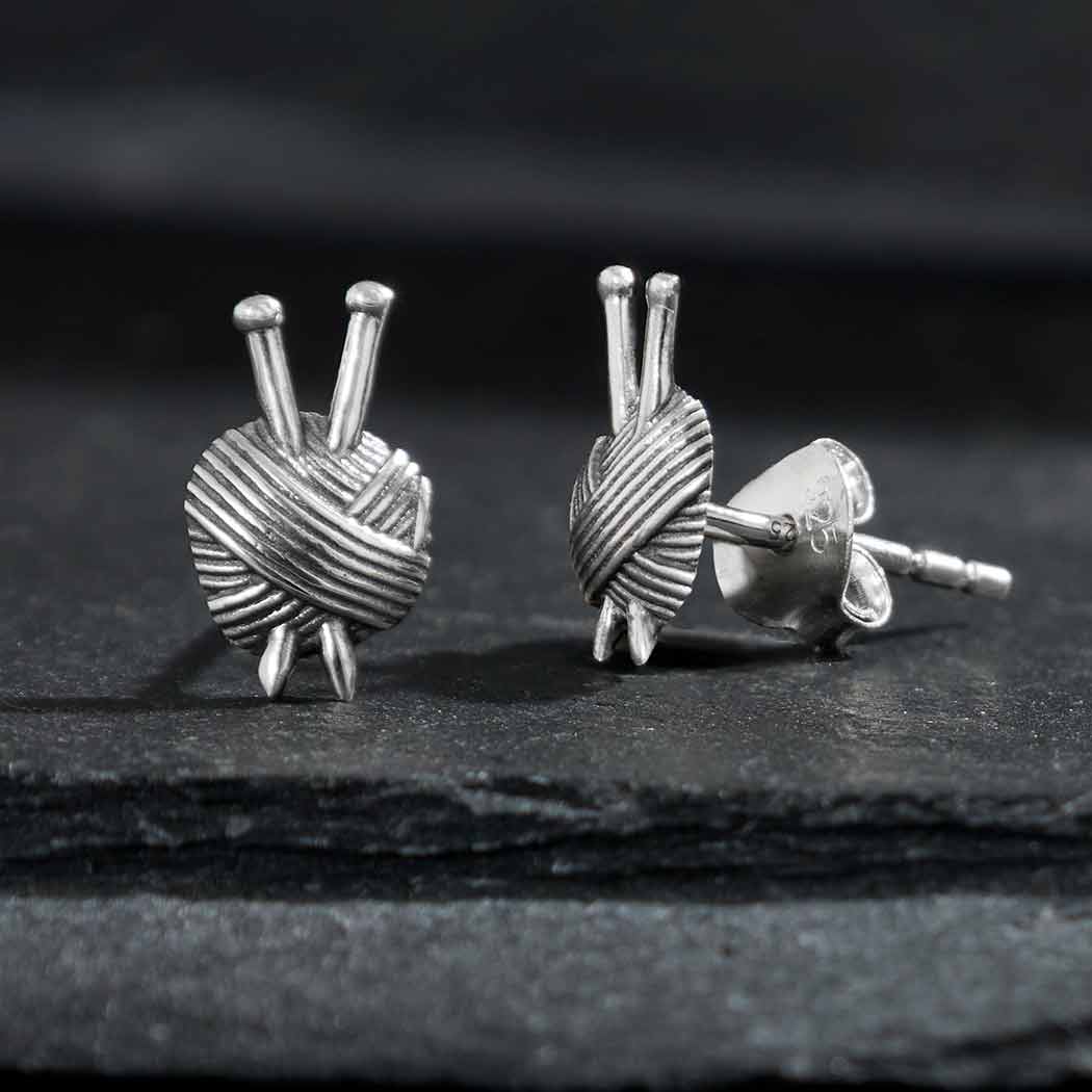 A pair of sterling silver yarn ball post earrings displayed against a dark background.