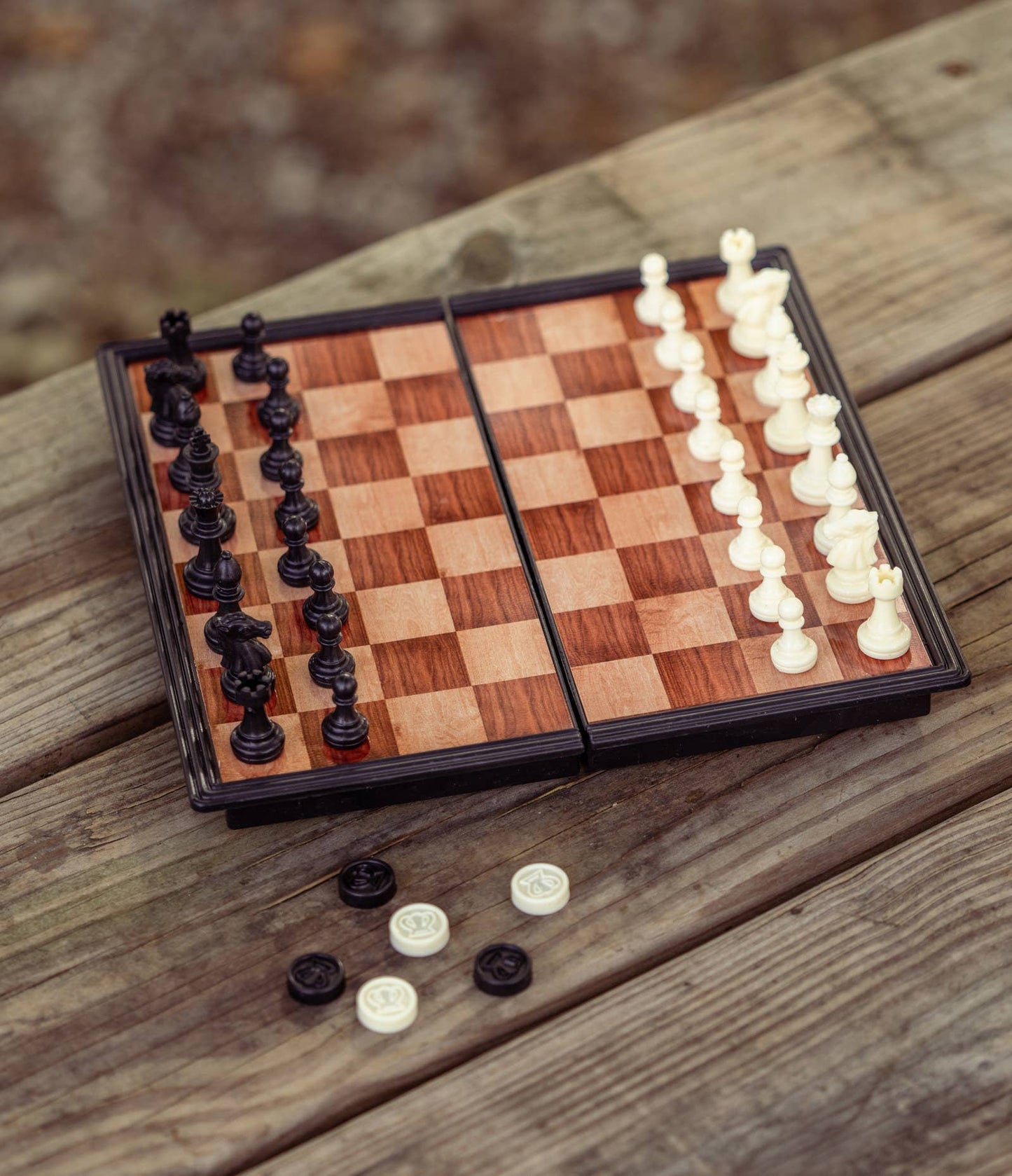 dark and light wood checkered board with chess pieces on top and checker pieces on the side