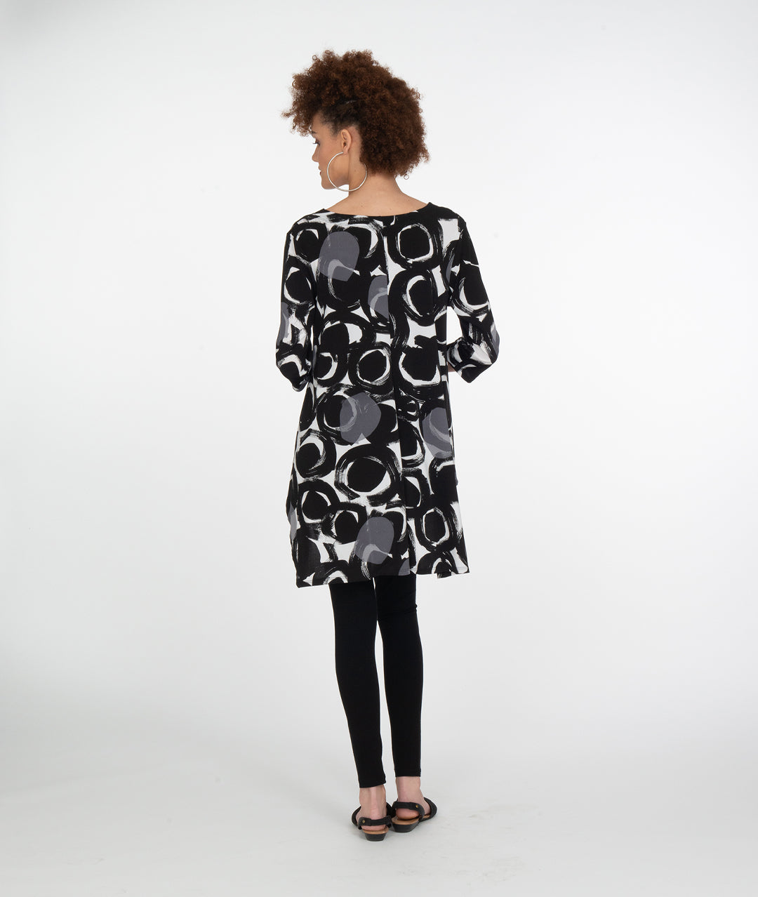 model in black leggings with a black, white and grey circle print tunic with a high-low hem and a vneck