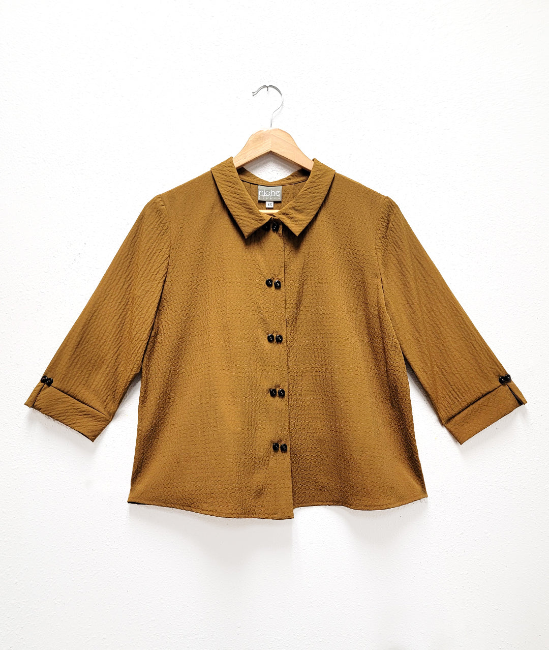 dijon yellow button down blouse with double sets of "twin" shell buttons down the front, easy a-line shape and straight hem. 3/4 length sleeves, with inverted pleat and open notched collar in back.