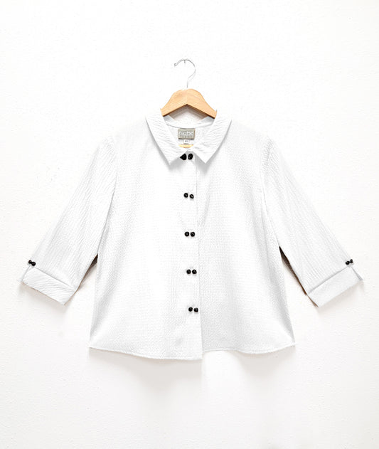white, seersucker textured top with double sets of "twin" shell buttons down the front, easy a-line shape and straight hem. 3/4 length sleeves, with inverted pleat and open notched collar in back.