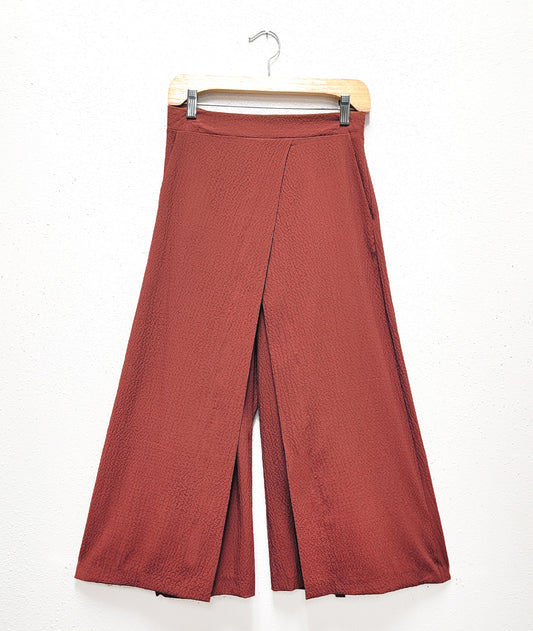 burnt sienna color wide leg pant with a wide waistband and an overlapping over layer in the front