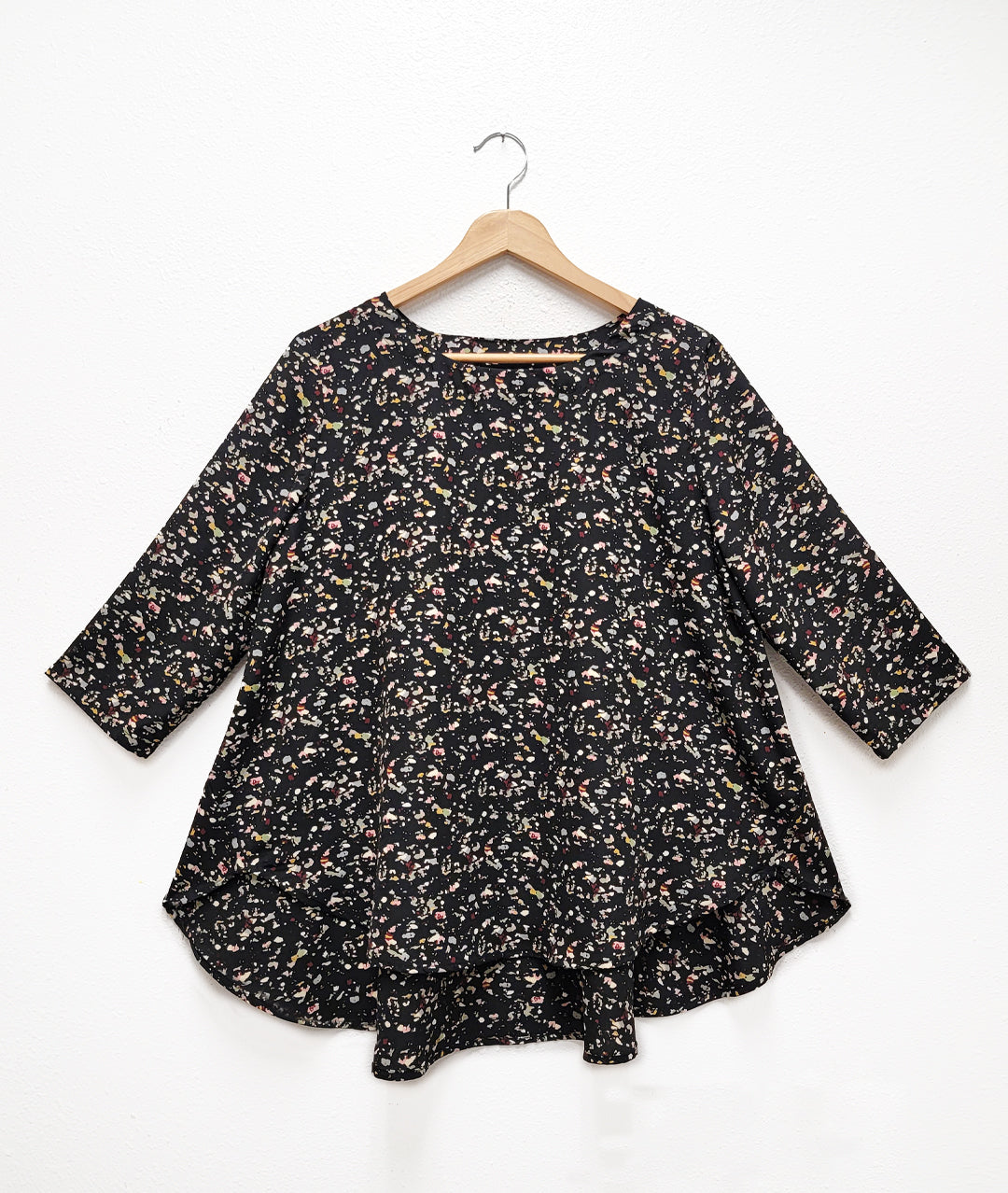 black terrazzo print pull over top with 3/4 sleeves, a round neckline and a flowy high-low body