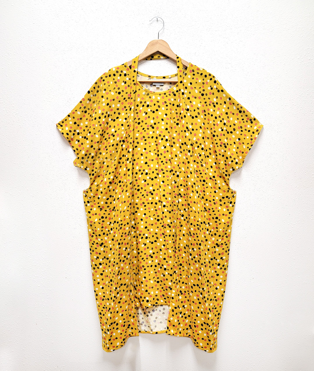 mustard yellow dress with a multicolor dot print. dress has extended hips connected by a band to be worn around the neck