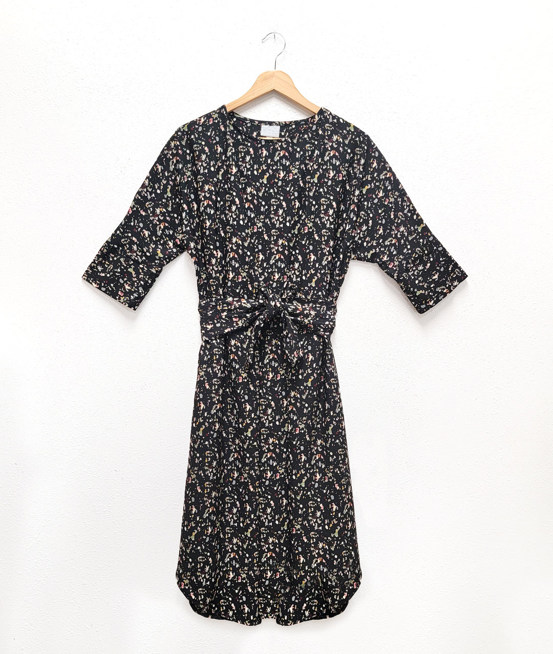 black terrazzo print dress with a kimono style sleeve and a center waist tie belt that can be worn in a number of ways
