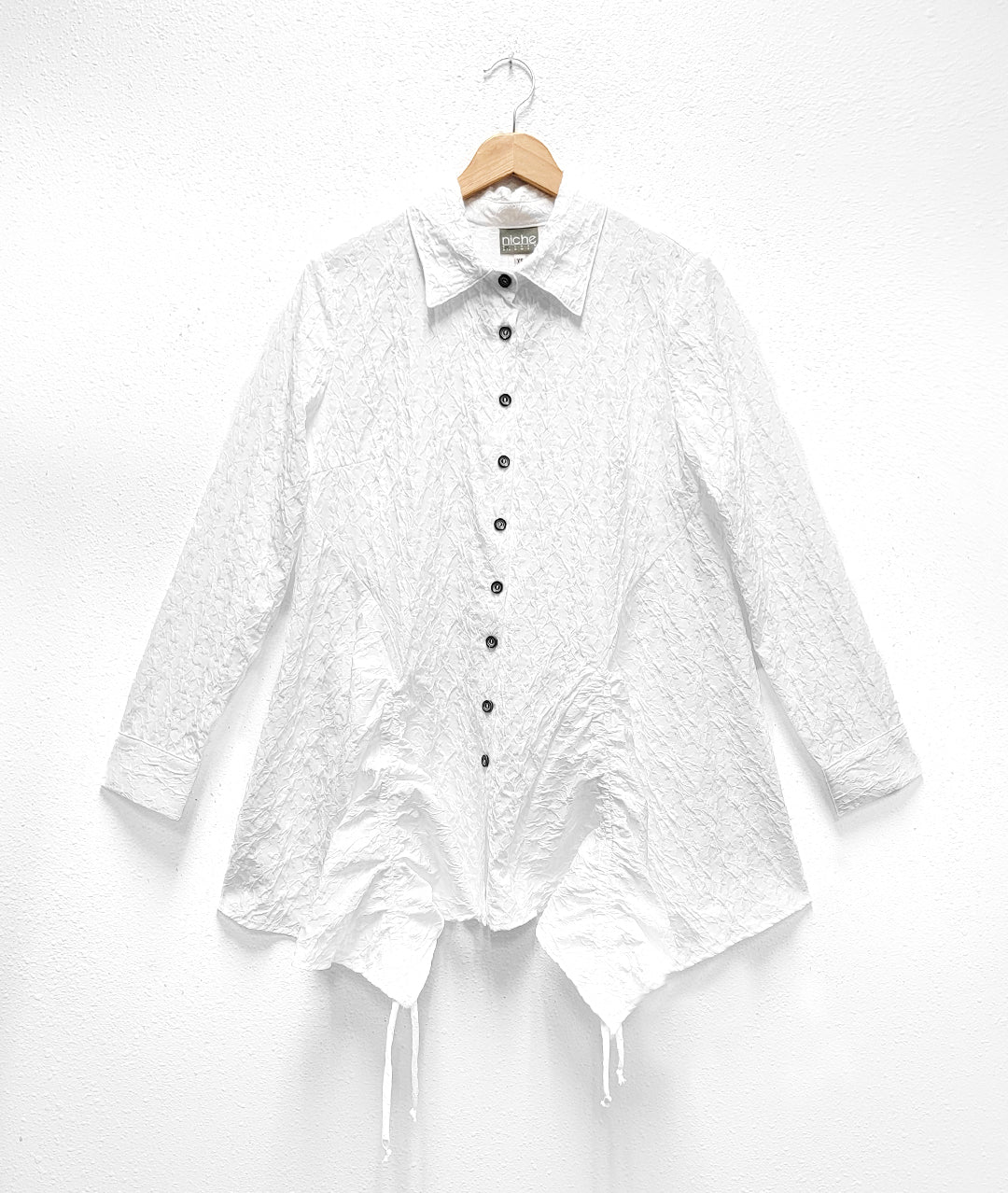 textured button down white blouse with long sleeves and a drawstring gather detail at each hip