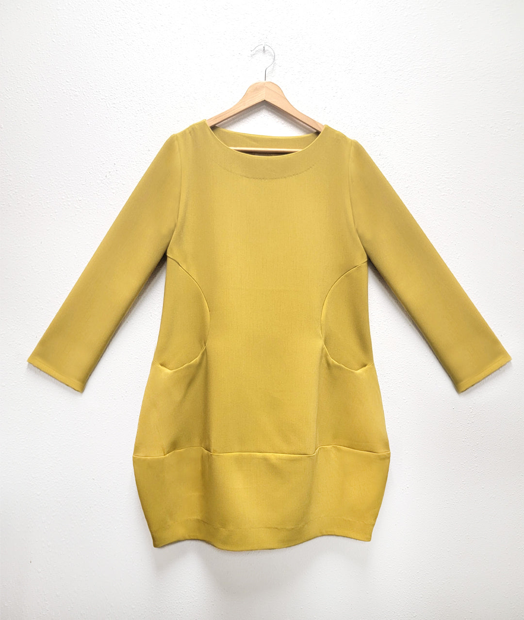 gold tunic with a wide bottom hem, 3/4 sleeves, and round seams at the waist with set in pockets