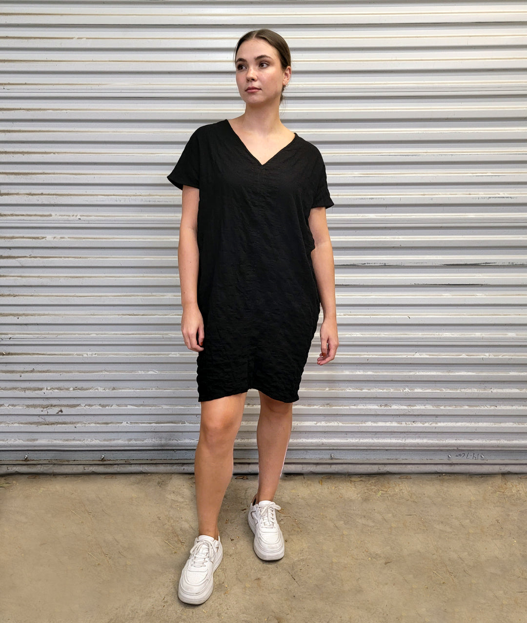 model in a black textured cocoon style dress with a v-neck