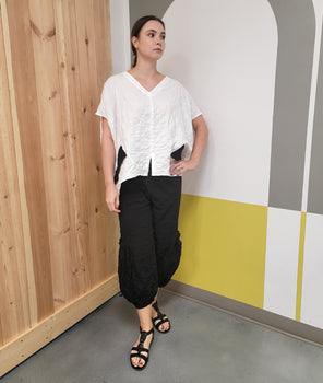model in a black pant with a dropped cargo pocket, worn with a white boxy top with a black panel on the side