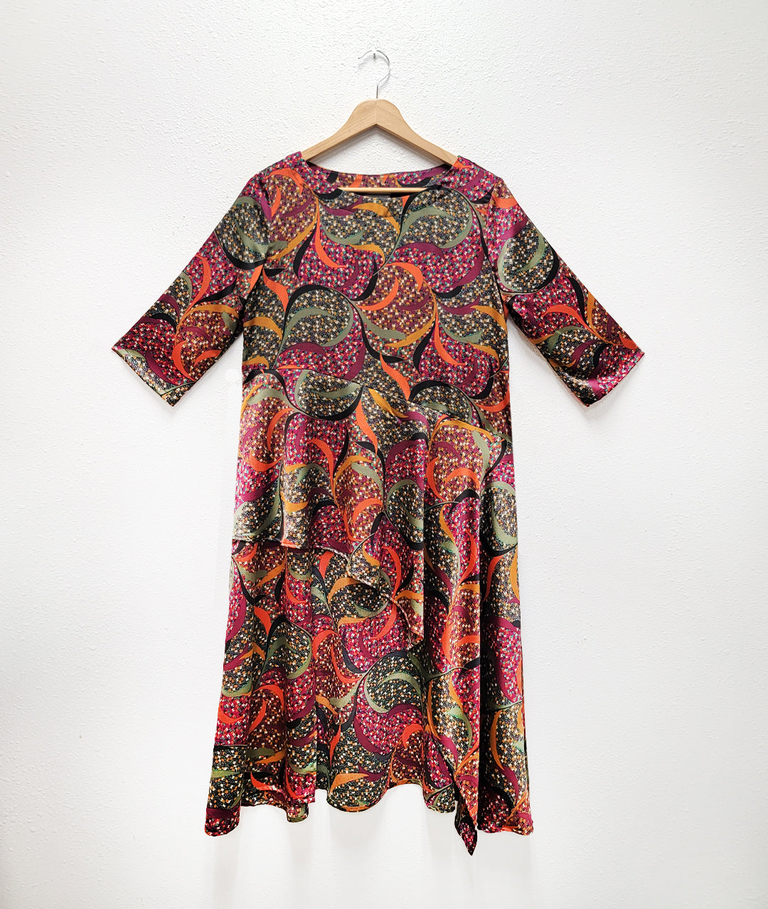 multi color swirl print tunic with elbow length sleeves and an asymmetrical waist and skirt, with a short front and long sides and back. pockets set into side seams