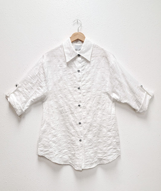 white textured button down blouse with rolled sleeves held with a small tab. black and white buttons.