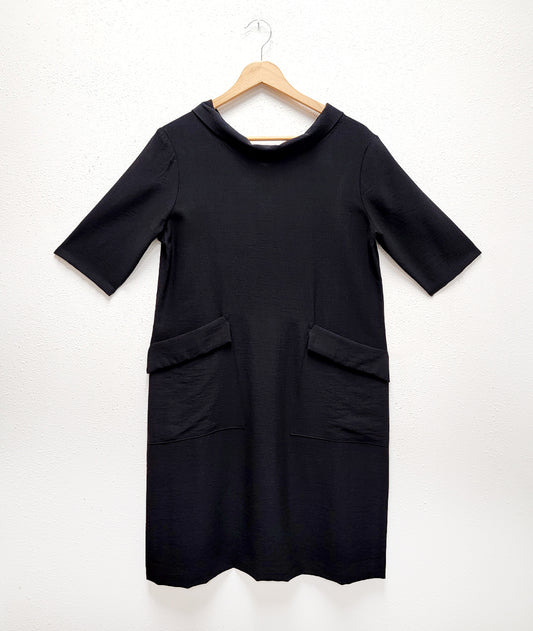 black knee length shift dress with elbow length sleeves, a round cowl neck collar and exterior hip pockets