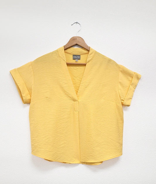 lemon yellow pullover top with cuffed short sleeves, a round hemline, and a vneck with a short standing collar and folded center front