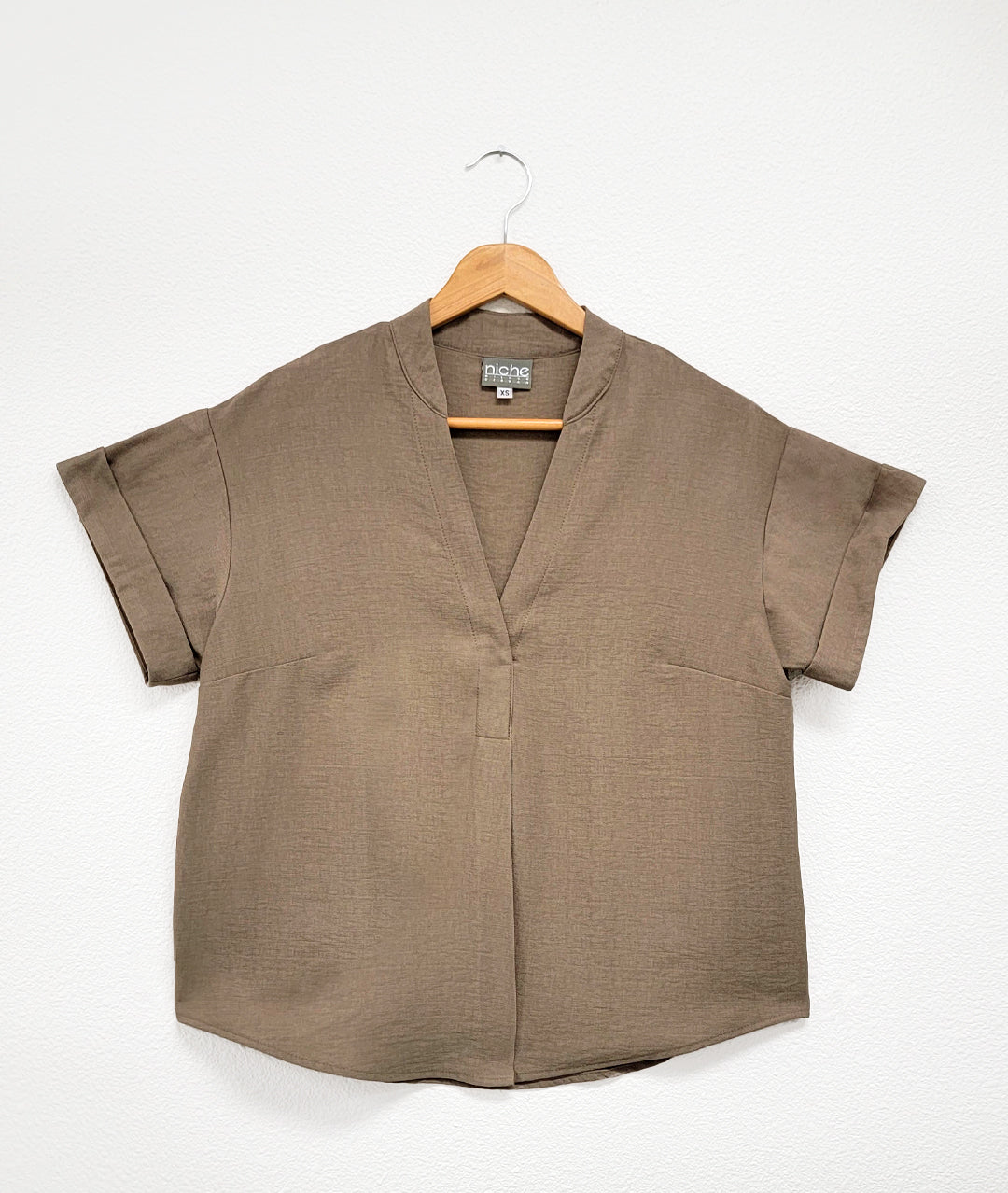 pebble brown pullover top with cuffed short sleeves, a round hemline, and a vneck with a short standing collar and folded center front
