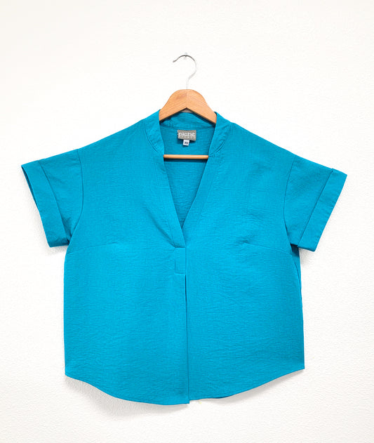 turquoise pullover top with cuffed short sleeves, a round hemline, and a vneck with a short standing collar and folded center front