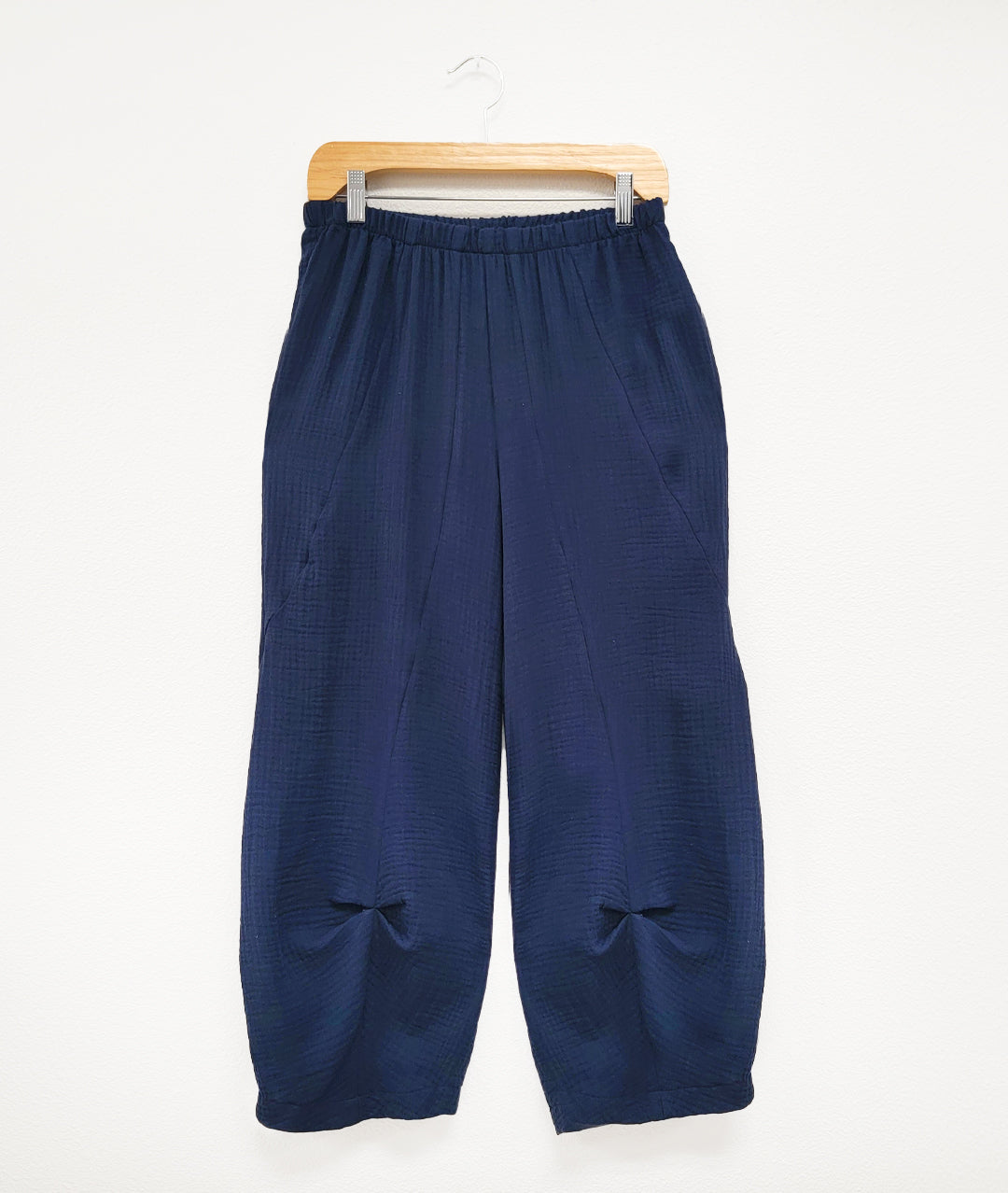 navy blue elastic waist pull on pant with pockets. Tulip shape with pinch pleats below the knee