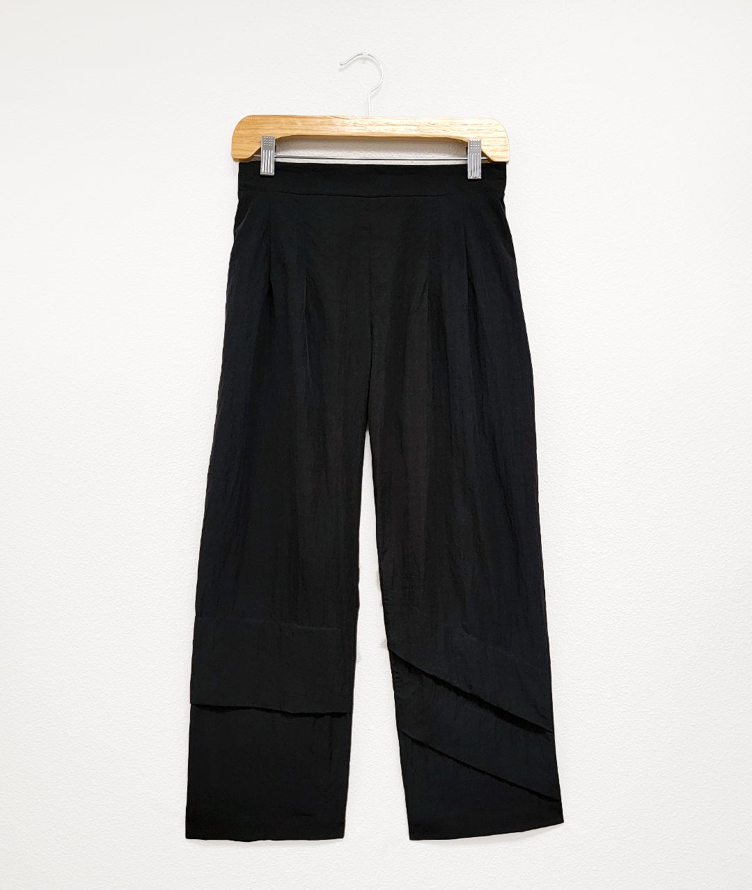 black straight cut black pants with an elastic waistband and asymmetrical deep pleat details at the calf of either leg