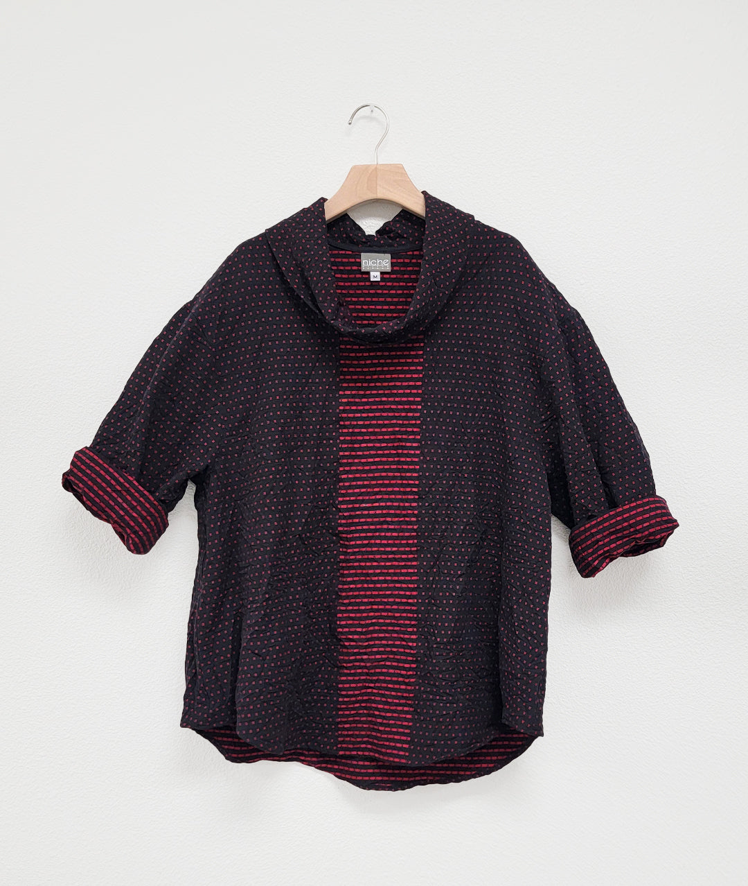 black and red patterened pullover top with a contrasting center panel, with a cowl neck and rounded hem