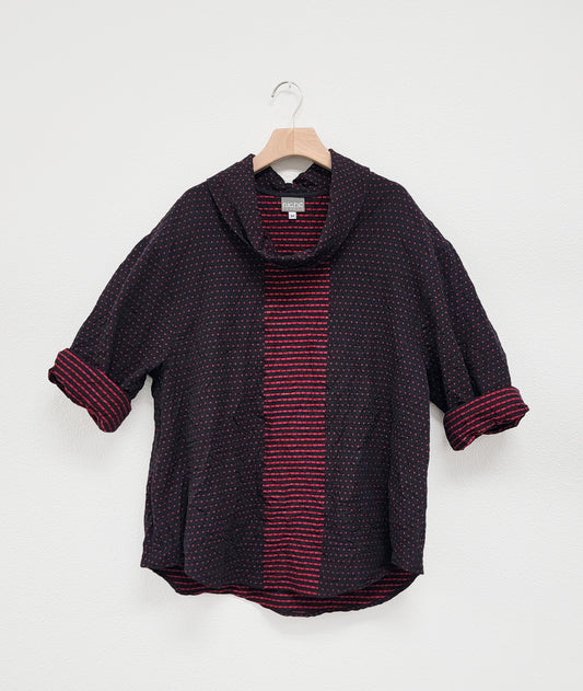 black and red patterened pullover top with a contrasting center panel, with a cowl neck and rounded hem