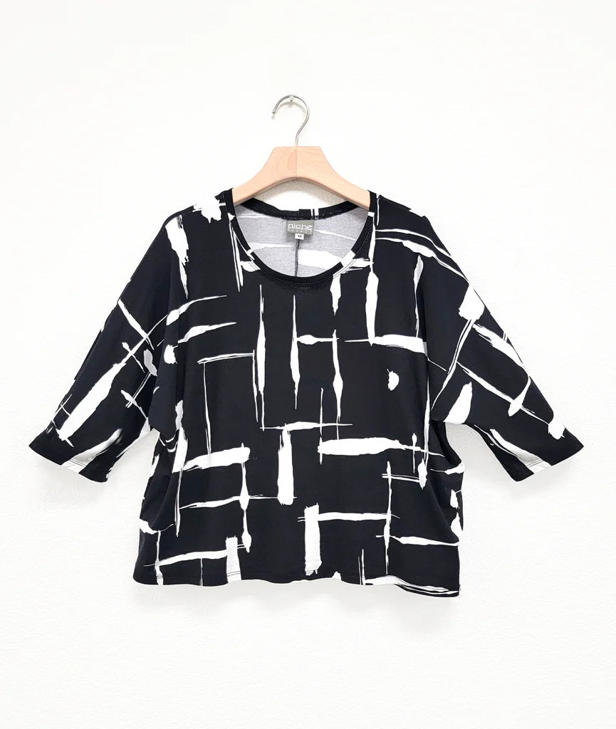 black and white print top with boxy cut, dolman sleeves, and a high neck on a hanger and white background